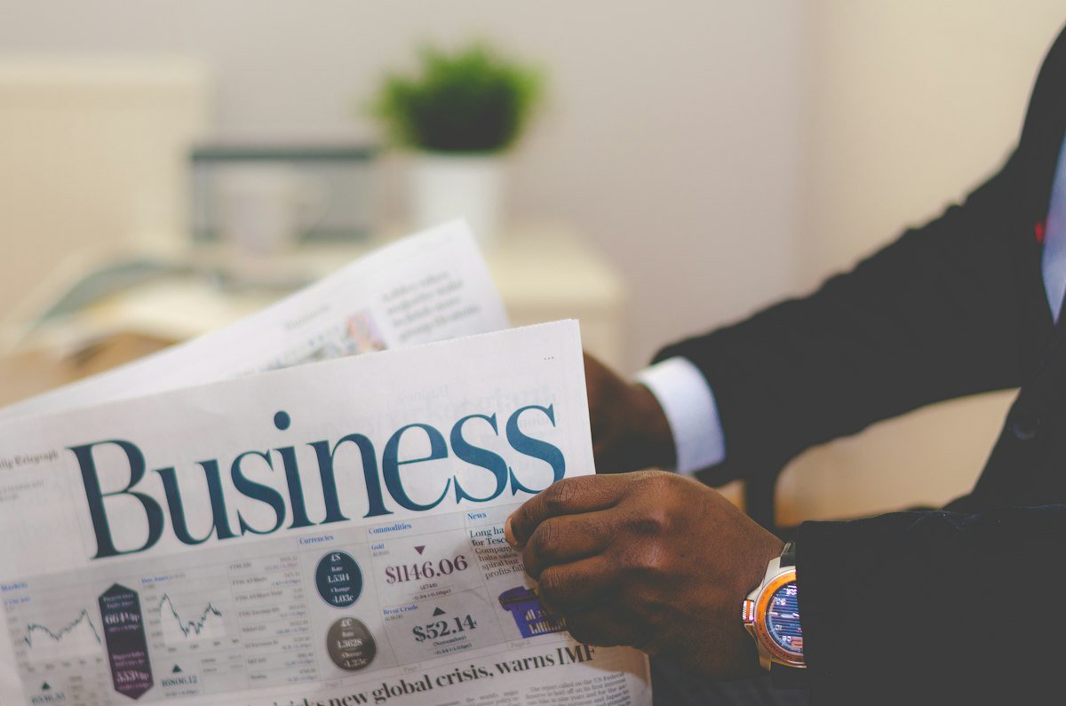 A reader reviewing a business newspaper